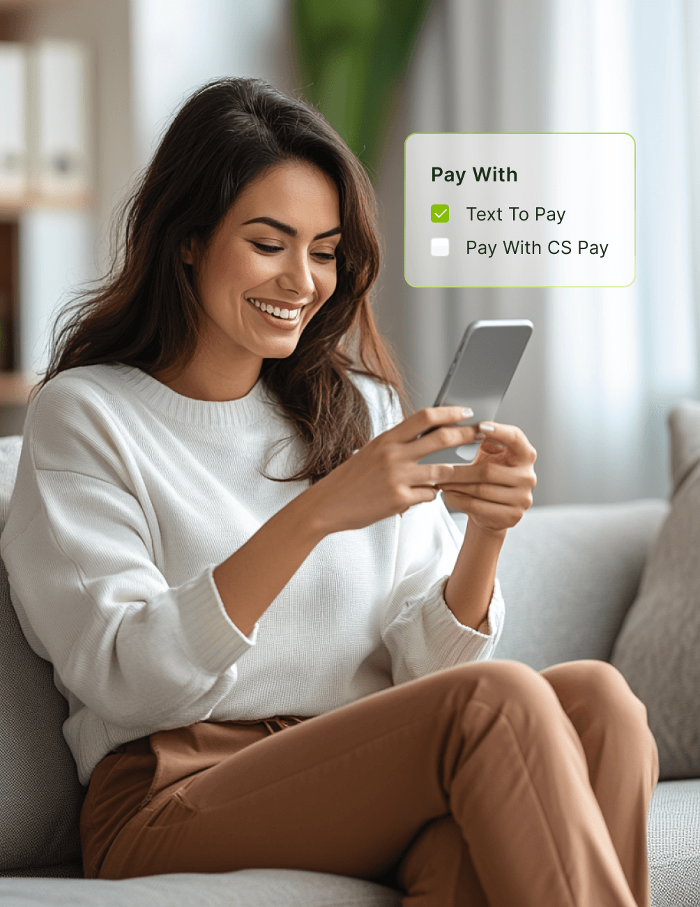 Smiling woman sitting on a couch using a smartphone with payment options displayed: "Text To Pay" checked, "Pay With CS Pay" unchecked.
