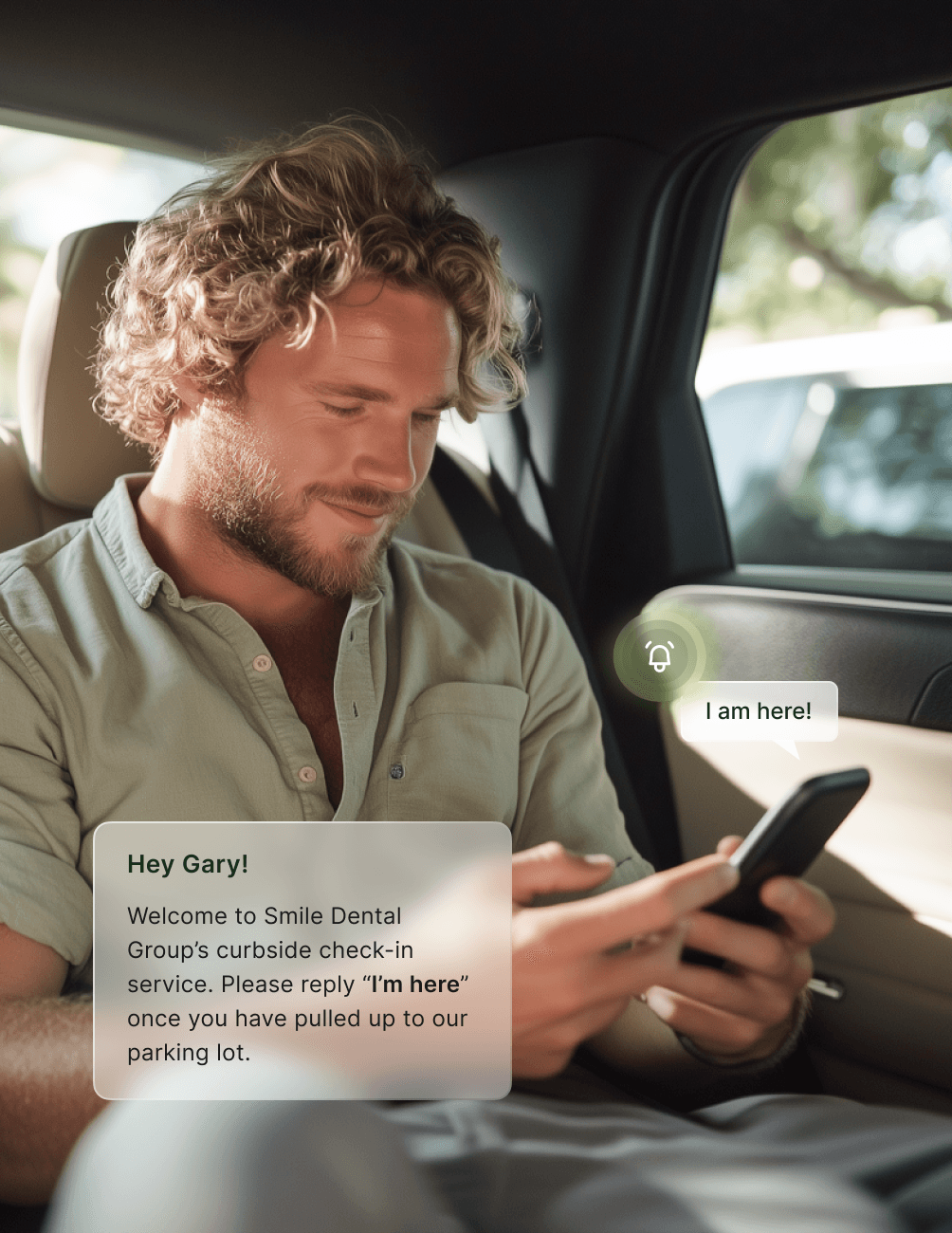 Man with curly hair in a car reads a text on his phone, confirming arrival for a dental appointment.